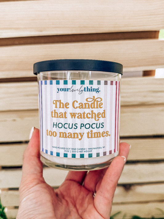 Candle with a humorous label held by a hand against a wooden background