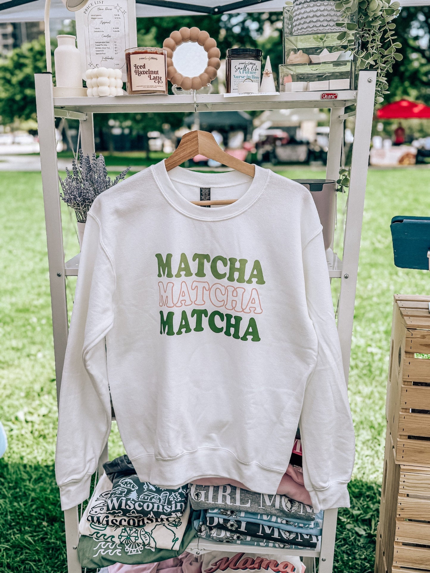 White sweatshirt with 'MATCHA MATCHA MATCHA' text on a hanger outdoors.