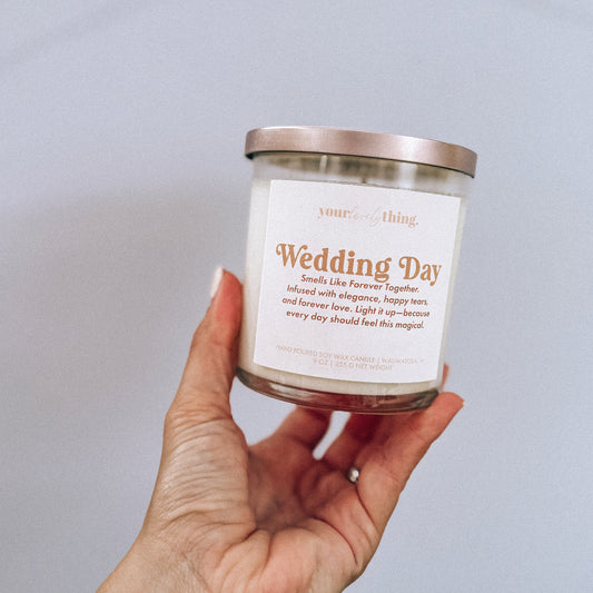 Hand holding a candle labeled 'Wedding Day' against a plain background
