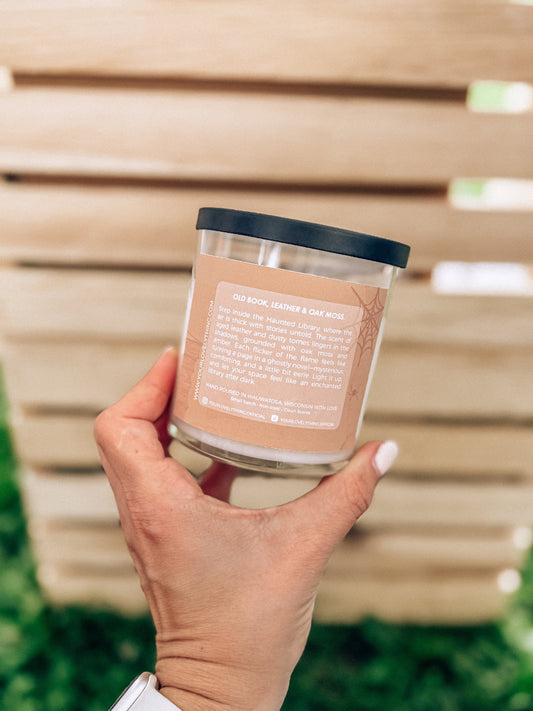 Hand holding a candle with a label against a neutral background