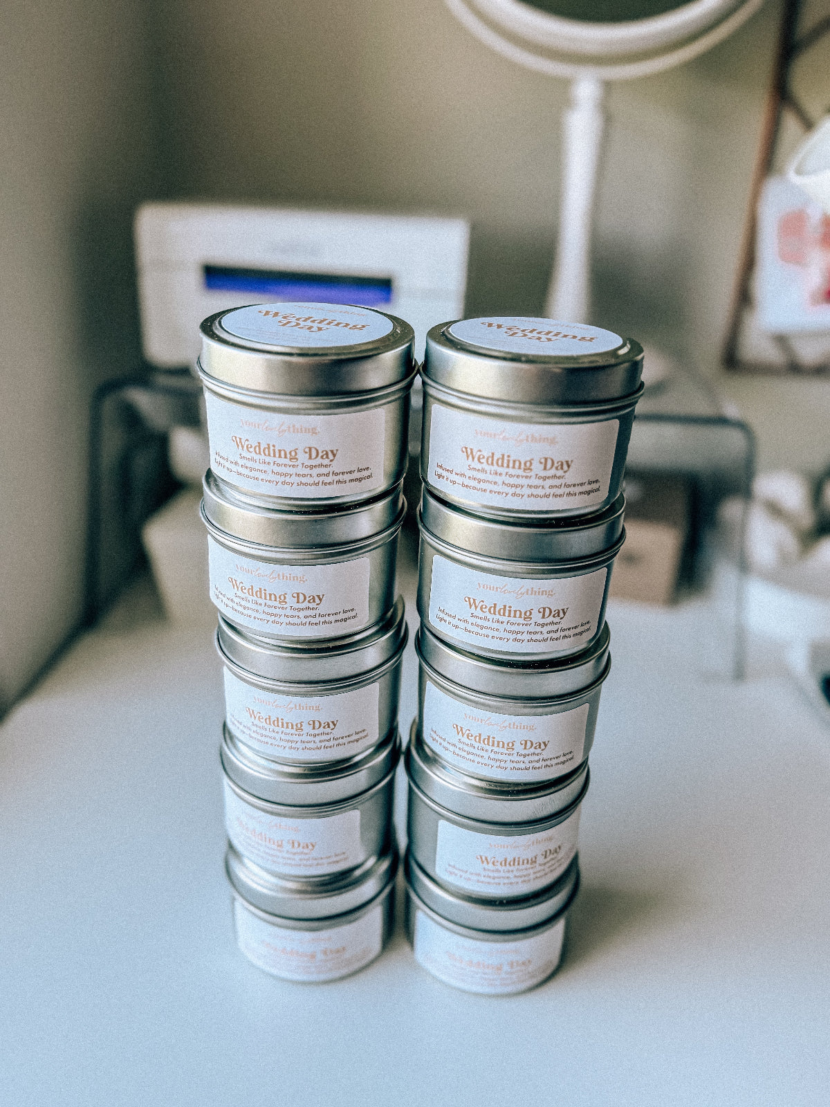 Stack of 'Wedding Day' scented candles in metal tins on a white surface.
