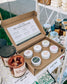 Box of candles with a label on a table with other candles and products.