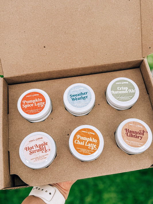 Set of six small containers with autumn-themed labels in a cardboard box.
